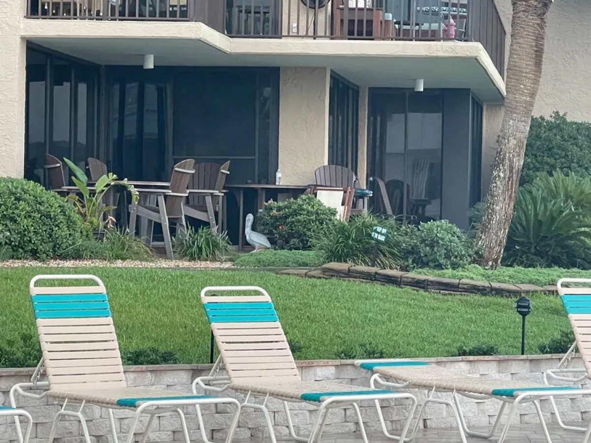 A vibrant poolside setup featuring lounge chairs, a green lawn, and a patio dining area. The scene is casual yet stylish, with ample room for groups to gather, eat, or relax after a day at the beach or local markets.