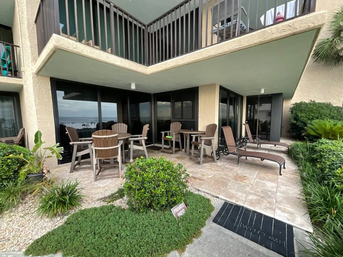 A private outdoor seating area with wooden chairs and tables, two lounge chairs for relaxation, and abundant greenery surrounding the patio. The space feels peaceful and extends a warm invitation for socializing or unwinding after a local outing.